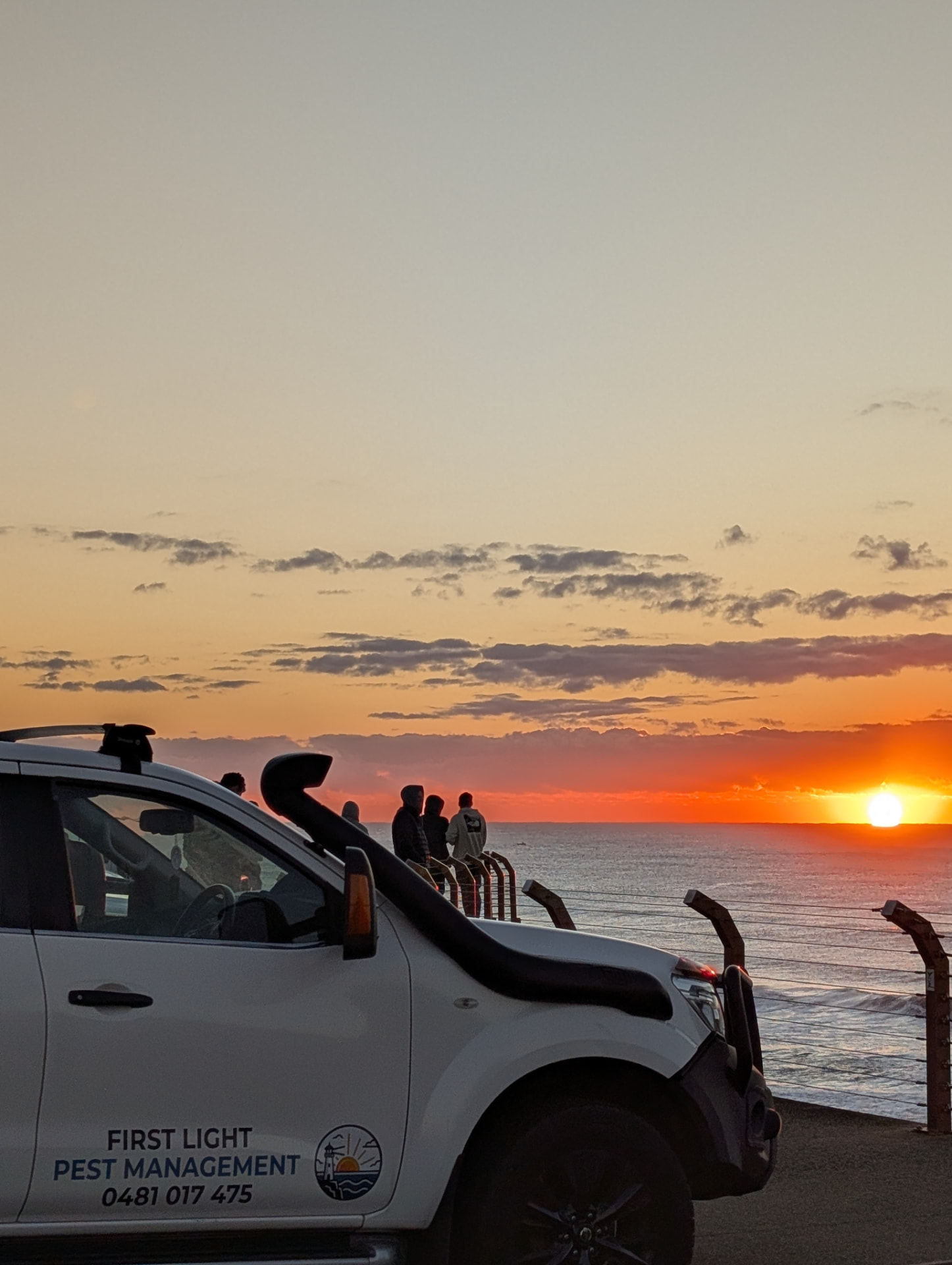 The First Light ute parked at a coastal lookout while people watch the sun rise over the ocean